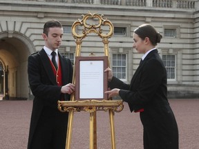 Footmen Stephen Kelly and Sarah Thompson bring out the easel in the forecourt of Buckingham Palace to formally announce the birth of a baby boy to  Britain's Prince Harry and Meghan, the Duchess of Sussex, in London, Monday, May 6, 2019.