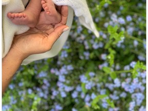 In this undated photo made available on Sunday, May 12, 2019 by @SussexRoyal, Meghan the Duchess of Sussex holds the feet of her baby, Archie Harrison Mountbatten-Windsor. Prince Harry and Meghan, the Duchess of Sussex, have released a photo of their newborn baby to mark Meghan's first Mother's Day as a mom. The image posted on Instagram shows her hand cradling the feet of Archie Harrison Mountbatten-Windsor, who was born on Monday, against a bed of spring flowers. (@SussexRoyal via AP)