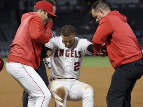 Los Angeles Angels' Andrelton Simmons, center, is helped up by manager Brad Ausmus, left, and a trainer after he was injured while being thrown out at first during the eighth inning of a baseball game against the Minnesota Twins Monday, May 20, 2019, in Anaheim, Calif.