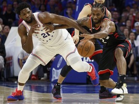 Toronto Raptors' Kawhi Leonard, right, reaches for the ball as he holds off Philadelphia 76ers' Joel Embiid, left, during the second half of Game 3 of a second-round NBA basketball playoff series Thursday, May 2, 2019, in Philadelphia.