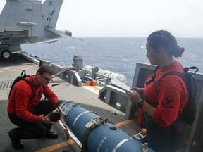 In this Wednesday, May 15, 2019, photo released by the U.S. Navy, Aviation Ordnanceman 3rd Class Alexandrina Ross, right, and Aviation Ordnanceman Airman Hunter Musil, left, inspect a bomb on the USS Abraham Lincoln while it sails in the Arabian Sea. U.S. diplomats warned Saturday, May 18, 2019, that commercial airliners flying over the wider Persian Gulf faced a risk of being "misidentified" amid heightened tensions between the U.S. and Iran.