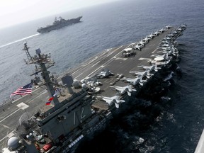 CORRECTS DATE - In this Friday, May 17, 2019, photo released by the U.S. Navy, the USS Abraham Lincoln sails in the Arabian Sea near the amphibious assault ship USS Kearsarge. Commercial airliners flying over the Persian Gulf risk being targeted by "miscalculation or misidentification" from the Iranian military amid heightened tensions between the Islamic Republic and the U.S., American diplomats warned Saturday, May 18, 2019, even as both Washington and Tehran say they don't seek war.