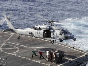 In this Sunday, May 19, 2019 photo, an MH-60S Sea Hawk helicopter transports cargo from the fast combat support ship USNS Arctic to the Nimitz-class aircraft carrier USS Abraham Lincoln during a replenishment-at-sea operation in the Arabian Sea, as Mideast tensions remain high between Tehran and the United States.