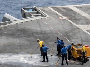 In this Sunday, May 19, 2019, photo released by the U.S. Navy, Sailors scrub the flight deck of the Nimitz-class aircraft carrier USS Abraham Lincoln in the Arabian Sea.