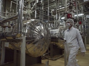 FILE - In this March 30, 2005 file photo, an Iranian security official in protective clothing walks through part of the Uranium Conversion Facility just outside the Iranian city of Isfahan. Iran threatened Wednesday, May 8, 2019, to resume higher enrichment of uranium in 60 days if world powers fail to negotiate new terms for its 2015 nuclear deal, an agreement that capped over a decade of hostility between Tehran and the West over its atomic program.