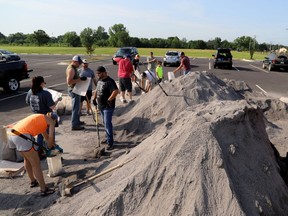 Volunteers fill sand bags at the soccer field parking lot in Chaffee Crossing, Ark., Saturday, May 25, 2019, for distribution throughout the area for flood prone areas around homes.