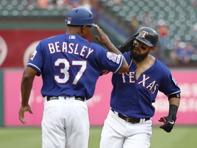 Texas Rangers third base coach Tony Beasley (37) salutes Rougned Odor, right, as Odor rounds the bag on his way home after hitting a three-run home run off of Seattle Mariners starting pitcher Mike Leake in the first inning of a baseball game in Arlington, Texas, Monday, May 20, 2019. The shot also scored Joey Gallo and Nomar Mazara.