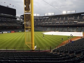 Members of the Pittsburgh Pirates warm up in the outfield of a tarp-covered Globe Life Park field as light rain showers pass through before a baseball game against the Texas Rangers in Arlington, Texas, Tuesday, April 30, 2019.