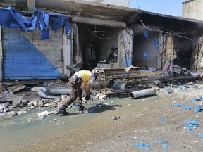 This photo provided by the Syrian Civil Defense White Helmets, which has been authenticated based on its contents and other AP reporting, shows a civil defense worker, works in front of damaged shops after shelling hit a street in the town of Ehssem, southern Idlib, Syria, Friday, May 3, 2019. Syrian state media and activists are reporting a wave of government and Russian airstrikes, including indiscriminate barrel bombs, on the rebel-held enclave in northwestern Syria where a seven-month truce is teetering under a violent escalation.