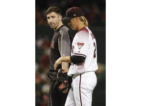 Arizona Diamondbacks starting pitcher Zack Greinke leaves the field with a trainer during the eighth inning of a baseball game against the Pittsburgh Pirates in Phoenix, Wednesday, May 15, 2019.