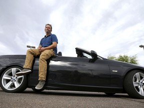 In this April 23, 2019, photo, Chris Williamson poses for a photo sitting on his car in Phoenix. When Williamson was in the market for a new family car, a timely ad and conversations with a co-worker convinced him to try something out of the ordinary. He bought the BMW 3 Series convertible and covers the payments by renting it to strangers on a peer-to-peer car sharing app called Turo. It allows his family of seven to have a nicer car, essentially for free.