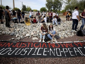 Students from Desert View High School sit by a banner after marching to the Pima County Sheriff's Department on Monday, May 6, 2019 in Tucson, Ariz. to protest the detention of their classmate, Thomas Torres, who was stopped by a sheriff's deputy on May 2 and was detained until Border Patrol arrived.