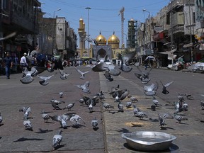 In this Wednesday, May 21, 2019, photo, pigeons fly outside the golden-domed shrine of Imam Moussa al-Kadhim in Kadhimiya district in north Baghdad, Iraq. Many shop owners in the Shiite holy neighborhood of Kadhimiya, have seen their sales drop sharply over the past year since U.S. President Donald began reimposing sanctions on Iran, home to the largest number of Shiite Muslims around the world.