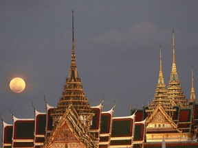 FILE - In this Jan. 31, 2018, file photo, a full moon rises behind the Grand Palace in Bangkok, Thailand. The official coronation of Thailand's King Maha Vajiralongkorn, who is also known as Rama X, involves months of rituals that will culminate in three days of elaborate pageantry, including a parade and an appearance by the king on a balcony of the Grand Palace. The final event will be a royal barge procession in October, 2019.