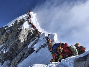 In this photo made on May 22, 2019, a long queue of mountain climbers line a path on Mount Everest. About half a dozen climbers died on Everest last week most while descending from the congested summit during only a few windows of good weather each May. (Nimsdai Project Possible via AP)