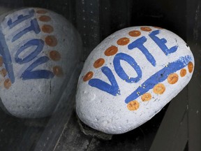 FILE - In this March 22, 2019, file photo, a stone painted with the word "VOTE" rests on the window sill of an art gallery in Peterborough, N.H. More than half of Americans want major changes to the system of government, including about 1 in 10 who want a complete overhaul. That's according to a new survey by the University of Chicago Harris School for Public Policy and The Associated Press-NORC Center for Public Affairs Research showing that dissatisfaction with the government system is closely tied with policy concerns.