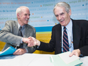 Charles Taylor, left and Gérard Bouchard shake hands after releasing their report on 