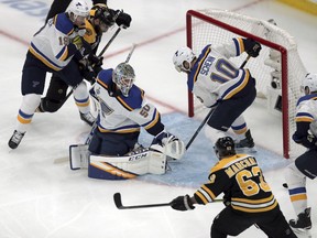 St. Louis Blues' Jay Bouwmeester, left, goaltender Jordan Binnington (50) and Brayden Schenn (10) defend an onslaught by Boston Bruins' Patrice Bergeron (37) and Brad Marchand (63) during the first period in Game 1 of the NHL hockey Stanley Cup Final, Monday, May 27, 2019, in Boston.