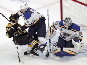 St. Louis Blues' Carl Gunnarsson (4), of Sweden, checks Boston Bruins' Jake DeBrusk (74) to the ice in front of Blues goaltender Jordan Binnington, right, during the first period in Game 2 of the NHL hockey Stanley Cup Final, Wednesday, May 29, 2019, in Boston.