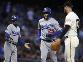Los Angeles Dodgers third base coach Dino Ebel, left, reacts as David Freese (25) runs the bases after hitting a three run home run off San Francisco Giants' Drew Pomeranz, right, in the fourth inning of a baseball game Tuesday, April 30, 2019, in San Francisco.