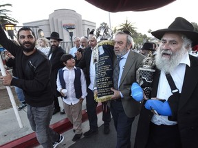 Howard Kaye, center, husband of Lori Kaye, carries the new Torah as Rabbi Yisroel Goldstein, right, and other members of the Chabad of Poway synagogue celebrate the completion of the new scroll dedicated to Lori Kaye, who was killed when a gunman attacked the synagogue in April on Wednesday, May 22, 2019, in Poway, Calif.