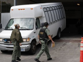 FILE - In this Tuesday, March 19, 2019 file photo, a van carrying asylum seekers from the border is escorted by security personnel as it arrives at immigration court, in San Diego. A federal appeals court ruled Tuesday, May 7, 2019, that the Trump administration can force asylum seekers to wait in Mexico for immigration court hearings while the policy is challenged in court, handing the president a major victory, even if it proves temporary.