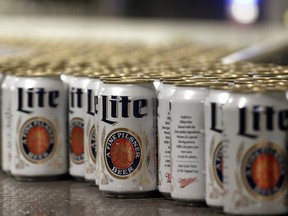 FILE - In this March 11, 2015 file photo, newly-filled and sealed cans of Miller Lite beer move along on a conveyor belt, at the MillerCoors Brewery, in Golden, Colo. A Wisconsin judge on Friday, May 24, 2019, ordered Anheuser-Busch to stop suggesting in advertising that MillerCoors' light beers contain corn syrup, wading into a fight between two beer giants that are losing market share to small independent brewers.