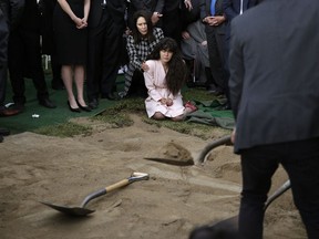 FILE - In this April 29, 2019, file, photo, Hannah Kaye, center, the daughter of Lori Kaye, who died when a man opened fire during Passover service inside a synagogue, sits on the ground with her aunt, Randi Grossman, as the last shovels of dirt cover her mother's grave during funeral services, in San Diego. Israeli researchers reported Wednesday, May 1, 2019, that violent attacks against Jews spiked significantly last year, with the largest reported number of Jews killed in anti-Semitic acts in decades, leading to an "increasing sense of emergency" among Jewish communities worldwide.