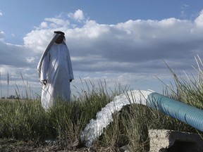 In this Tuesday, April 23, 2019, photo, a farmer stands near a water pump on his farm in Youssifiyah, Iraq. In the farming region, just south of the capital, canals that were empty last year are flush with water, and wells that were dug 24 meters deep to reach a sinking water table are producing water at just 6 meters depth.