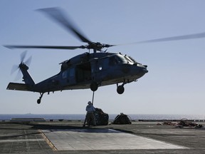 In this Friday, May 10, 2019 photo released by the U.S. Navy, logistics specialists attach cargo to an MH-60S Sea Hawk helicopter on the flight deck of the Nimitz-class aircraft carrier USS Abraham Lincoln in the  Persian Gulf. The  aircraft carrier strike group is being deployed to the Persian Gulf to counter an alleged but still-unspecified threat from Iran.