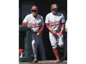 In this photo taken April 9, 2019, Stanford catcher Maverick Handley, right, walks out of the dugout next to coach David Esquer during an NCAA college baseball game against San Francisco in San Francisco. Handley is preparing to get drafted in June, and he has quite a fallback plan: going to medical school one day to become an orthopedic surgeon.