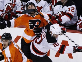 FILE - In this Jan. 8, 2011, file photo, Philadelphia Flyers' Daniel Carcillo, top, is hit in the face by a stick from New Jersey Devils' Rod Pelley during the third period of an NHL hockey game, in Philadelphia. Carcillo is hurting inside and out after seven documented concussions in the National Hockey League and what he believes could be hundreds of traumatic brain injuries. He doesn't remember any of his first five concussions but can't escape the anxiety, depression, lack of impulse control and suicidal thoughts now.