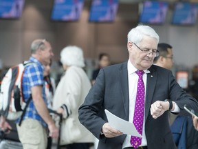 Federal Minister of Transport Marc Garneau walks past passengers at Toronto Pearson Airport, in Mississauga, Ont., Friday, May 24, 2019, after making an announcement regarding new rules to protect air passengers' rights.