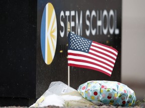 An American flag unfurls in the wind in a small tribute placed below the sign for STEM School Highlands Ranch following Tuesday's shooting, in Highlands Ranch, Colo., Thursday, May 9, 2019.