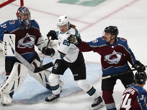 San Jose Sharks left wing Marcus Sorensen, center, swings at the puck as it flies past Colorado Avalanche defenseman Samuel Girard, right, while goaltender Philipp Grubauer protects the net during the first period of Game 4 of an NHL hockey second-round playoff series Thursday, May 2, 2019, in Denver.