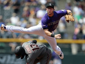 Colorado Rockies second baseman Ryan McMahon (24) throws to first base, after forcing out Arizona Diamondbacks shortstop Nick Ahmed (13) at second, for a double play in the second inning of a baseball game in Denver, Thursday, May 30, 2019.