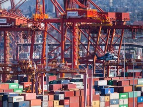 A Helijet helicopter preparing to land at the harbour passes by cranes used to load and unload container ships at the DP World marine terminal at Port Metro Vancouver, in Vancouver on March 16, 2018. Talks continued through the night between British Columbia's longshore workers union and the association representing port employers. A federal mediator imposed a news blackout as the latest round of negotiations got underway Wednesday, less than 24 hours before a lockout notice issued by the B.C. Maritime Employers Association was due to take effect.