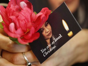 A woman holds a flower and a photo of Christine Wood during a vigil in Winnipeg, Wednesday, April 12, 2017. A jury has heard that blood from a woman whose body was found in a shallow grave near Winnipeg close to a year after her disapperance was discovered in the home of the man accused of killing her.