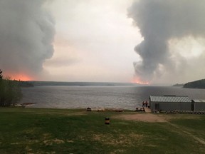 Fires burn in Little Grand Rapids, Man., as shown in a 2018 Government of Manitoba handout photo. Three people have been charged with arson for allegedly starting a wildfire in east-central Manitoba that forced 2,000 people from their homes last May. Residents of the fly-in Little Grand Rapids and Pauingassi First Nations were evacuated for more than a month.
