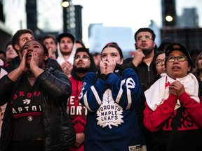 People watch the NBA Toronto Raptors and the NHL Maple Leafs on large outdoor screens in Maple Leaf Square in Toronto on Tuesday, April 23, 2019. It's hooked casual sports fans, ensnared pop culture junkies and most notably, enticed diehard Leafs fans to put aside their blue-and-whites to cheer for Canada's sole NBA team. But Toronto has always been a hockey town, and even this remarkable Raptors run likely won't change that, say observers including bar manager Adam Zizzo.