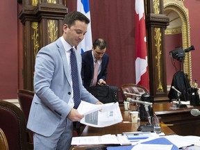 Quebec Minister of Immigration, Diversity and Inclusiveness Simon Jolin-Barrette picks up documents on the first day of a legislature committee studying a bill on secularism, Tuesday, May 7, 2019 at the legislature in Quebec City. Hearings into Quebec's secularism bill veered off track Thursday when a former senator drew a connection between the Muslim head scarf, female genital mutilation and forced marriage.