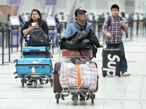 Passengers push their luggage through the departure terminal at Toronto Pearson Airport, in Mississauga, Ont., Friday, May 24, 2019. Air Canada says it is experiencing a system-wide technical issue affecting its airport operations, check-in and call centres.