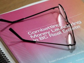 Glasses rest on a copy of Peter German's investigation report into money laundering in the B.C. real estate industry during a press conference in Victoria, B.C., on Thursday, May 9, 2019.