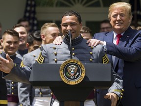 Army running back Darnell Woolfolke speaks as President Donald Trump grabs his shoulders during the presentation of the Commander-in-Chief's Trophy to the U.S. Military Academy at West Point football team, in the Rose Garden of the White House, Monday, May 6, 2019, in Washington.