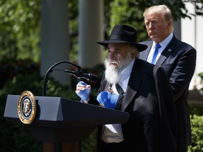 President Donald Trump looks on as Rabbi Yisroel Goldstein, survivor of the Poway, Calif synagogue shooting, speaks during a National Day of Prayer event in the Rose Garden of the White House, Thursday, May 2, 2019, in Washington.