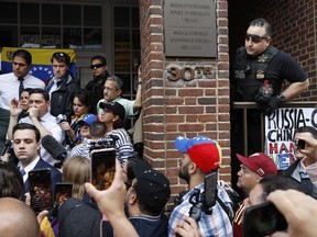 With Secret Service Police on site, Venezuelan ambassador Carlos Vecchio, on microphone at left, speaks to supporters of opposition leader Juan Guaido outside the Venezuelan embassy, Wednesday May 1, 2019, in Washington. The protesters want the protest groups Code Pink and ANSWER Coalition to be removed from inside the Venezuelan embassy where they've been staying for the past two weeks.