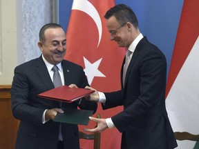 Hungarian Minister of Foreign Affairs and Trade Peter Szijjarto, right, and Turkish Foreign Minister Mevlut Cavusoglu exchange documents after signing an agreement at the Ministry of Foreign Affairs and Trade in Budapest, Hungary, Friday, May 3, 2019.
