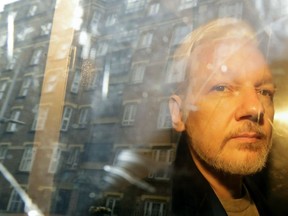 FILE - In this Wednesday May 1, 2019 file photo, buildings are reflected in the window as WikiLeaks founder Julian Assange is taken from court, where he appeared on charges of jumping British bail seven years ago, in London. Swedish prosecutors plan to decide whether they will reopen a rape case against WikiLeaks founder Julian Assange.
