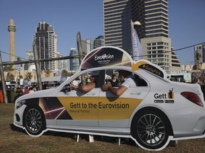 People pose in a cutout taxi cab ahead of the 2019 Eurovision Song Contest in Tel Aviv, Israel, Monday, May 13, 2019.
