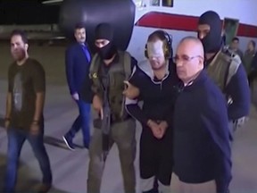 In this frame grab from Egyptian State Television, a blindfolded Hisham el-Ashmawi, a prominent Egyptian militant is escorted by Egyptian military officers and placed in a vehicle after being taken off a military plane at an airport in Cairo, Egypt, Wednesday, May 29, 2019. El-Ashmawi was captured last October in the Libyan city of Derna, a longtime bastion of Islamic militants, by commander Khalifa Hifter's self-styled Libyan National Army. (Egyptian State Television via AP)